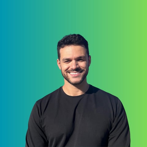 Smiling man with dark hair wearing a black long-sleeve shirt against a blue-to-green gradient background